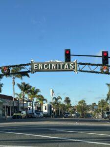 Encinitas downtown street view in San Diego with the iconic Encinitas sign, palm trees, and local storefronts on a sunny day, photographed by WeLease Property Management.